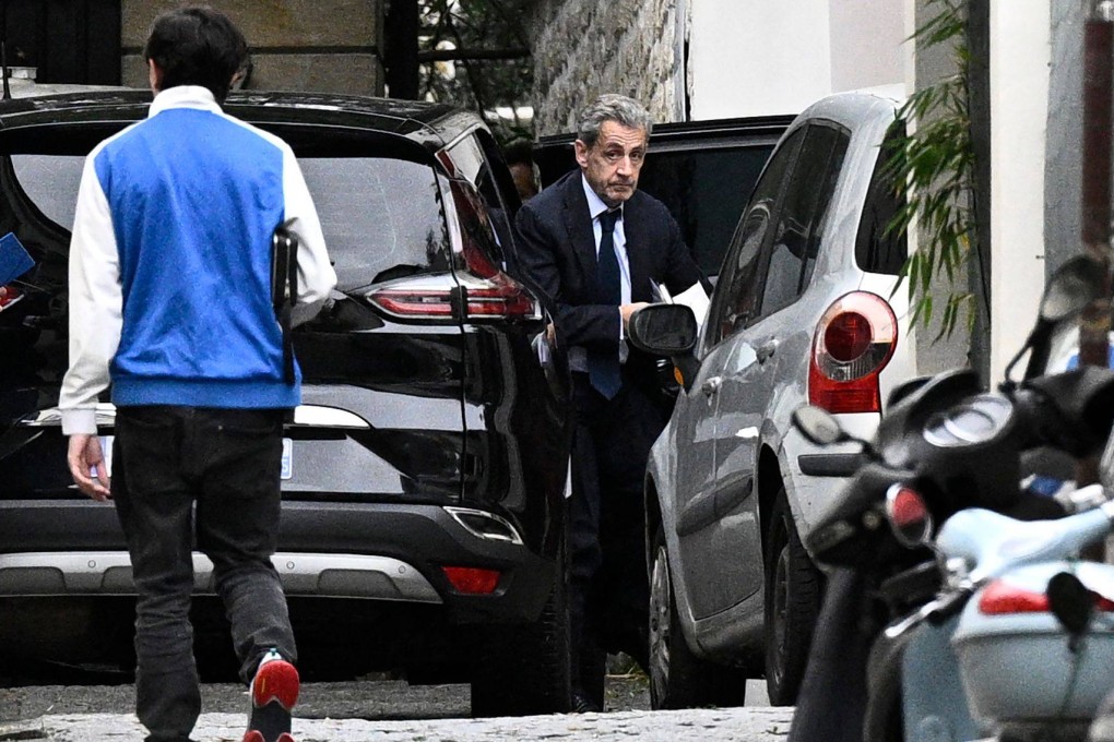 Nicolas Sarkozy exits a vehicle as he returns to his home in Paris following his meeting with prosecutors to be informed of the start of his jail sentence. Photo: AFP