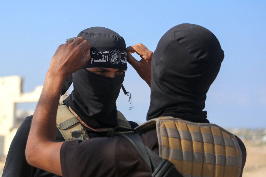 A Hamas fighter fixes the headband on his comrade’s forehead. Photo: AFP