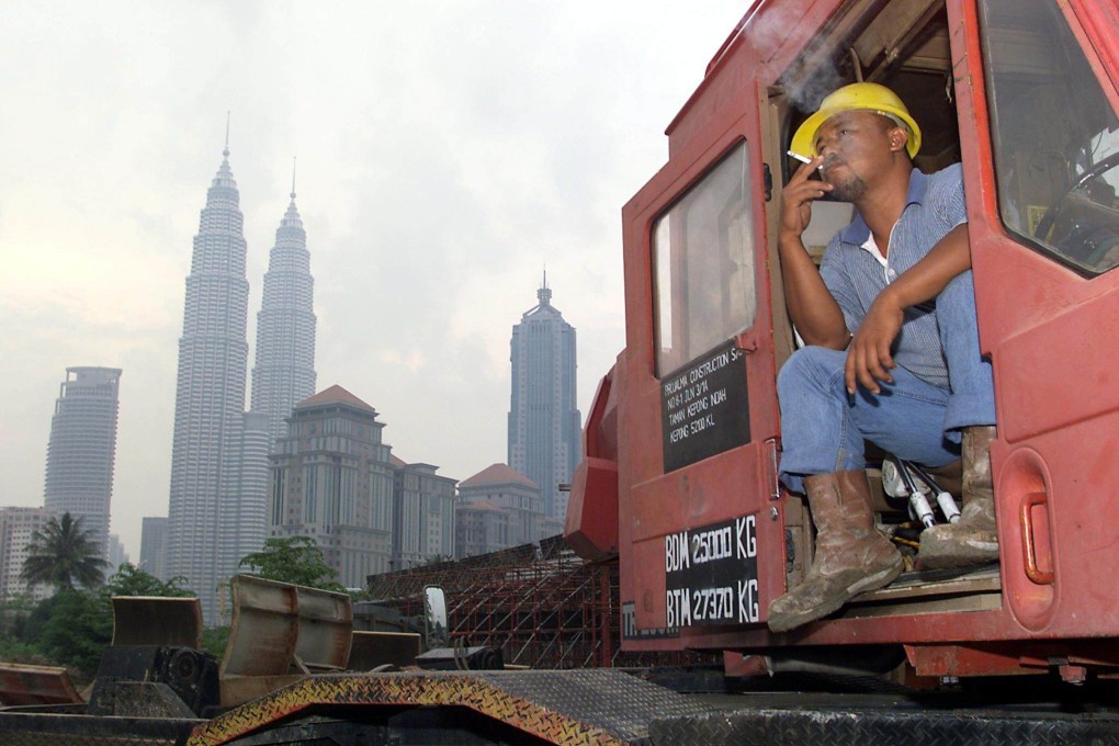 A construction worker smokes a cigarette in Kuala Lumpur with the Petronas Twin Towers in the background. Photo: AFP