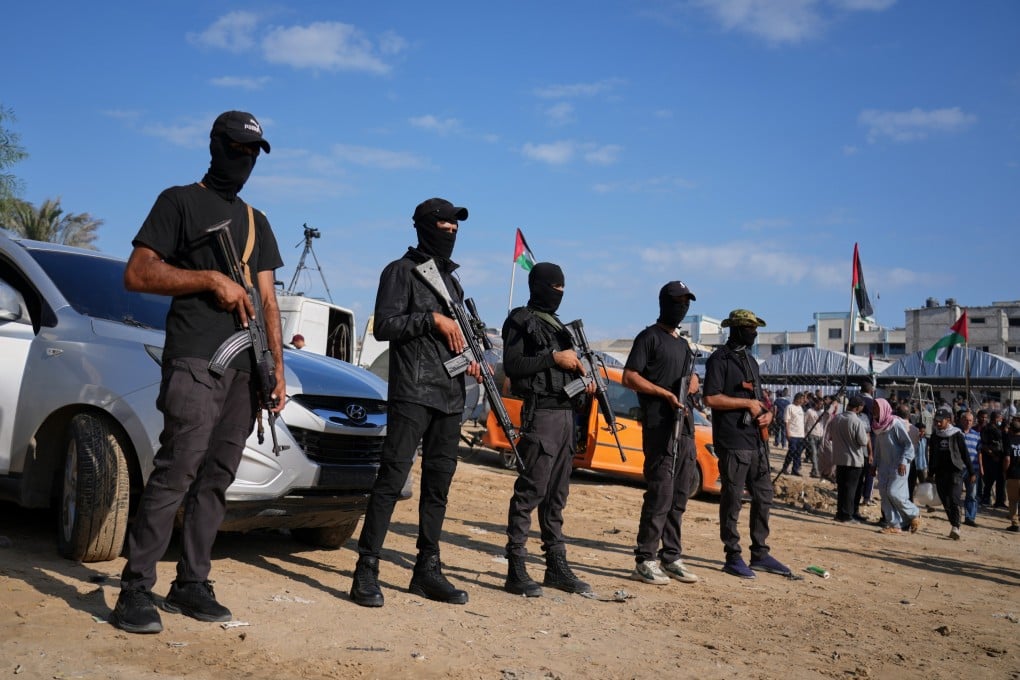 Hamas gunman stand guard as Red Cross vehicles transporting released Israeli hostages head toward the Israeli border in Khan Younis on Monday. Photo: AP