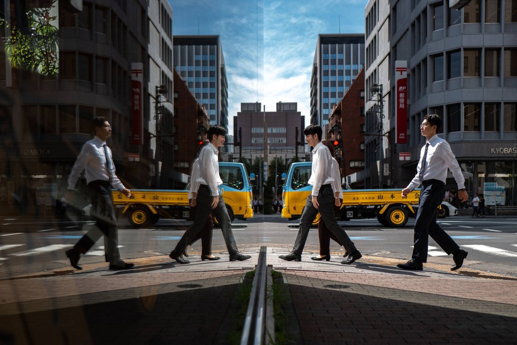 Pedestrians and vehicles are reflected in glass in the Ginza district of Tokyo on October 8, 2025. Photo: AFP