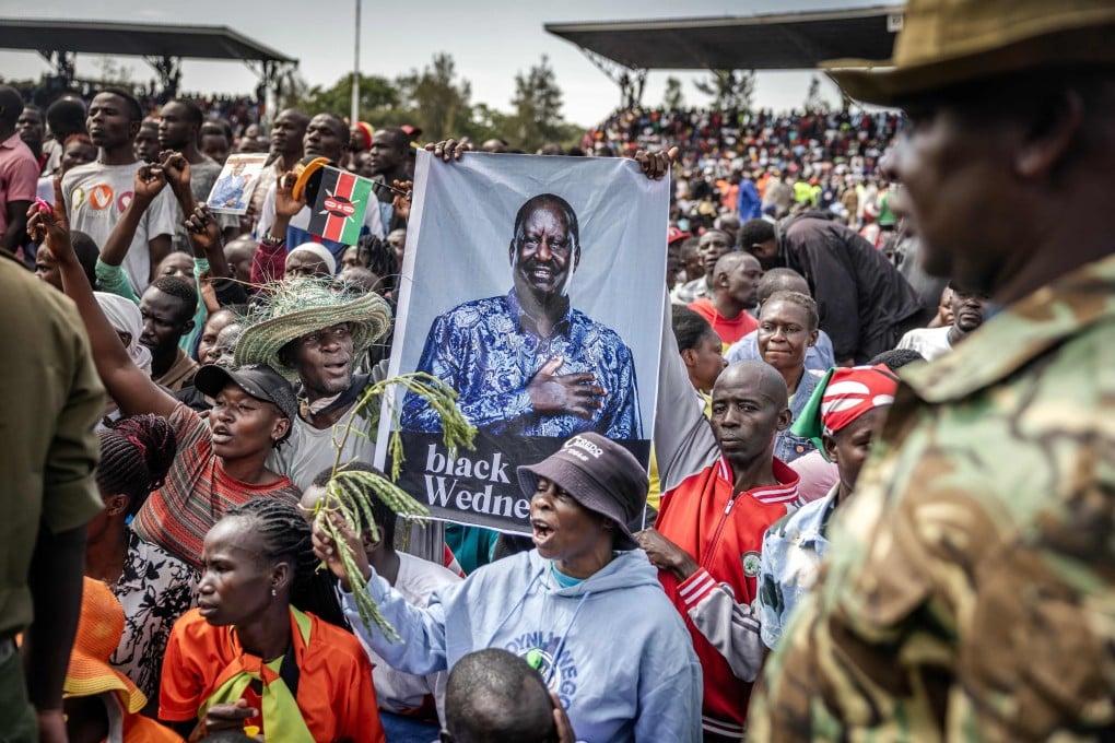 Supporters of Kenyas opposition leader Raila Odinga hold a banner as mourners line up to view his coffin upon the arrival of his funeral proceedings in Kisumu, Kenya, on Saturday. Photo: AFP