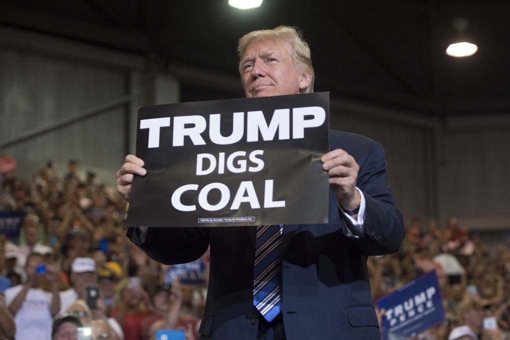 US President Donald Trump holds up a sign reading “Trump Digs Coal” in 2017, the year he first pulled out of the Paris Agreement on climate change. Photo: AFP/Getty Images/TNS