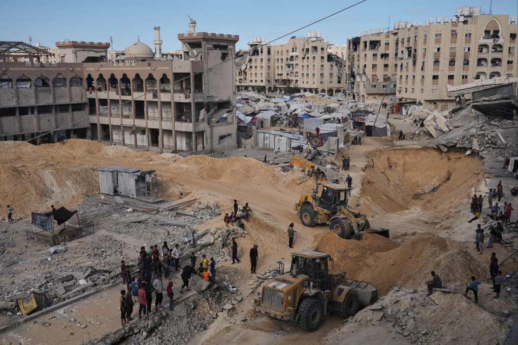 Palestinians watch members of the Hamas militant group search for bodies of the hostages in an area in Hamad City, Khan Younis, in the southern Gaza Strip on Saturday. Photo: AP