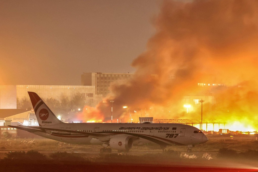 An airline plane stands on the tarmac as firefighters try to extinguish a fire that broke out in the cargo section of Hazrat Shahjalal International Airport in Dhaka on Saturday. Photo: AFP