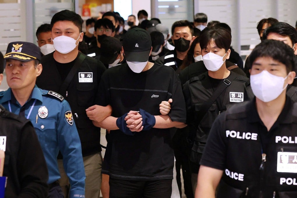 Police officers escort repatriated South Koreans who were detained by authorities in Cambodia over alleged cyberscam operations upon their arrival at Incheon International Airport on Saturday. Photo: Yonhap/AFP