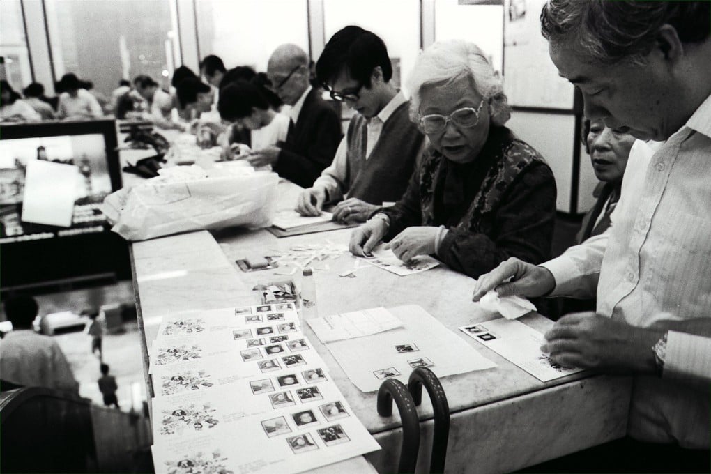 Eager philatelists in Hong Kong carefully stick a set of stamps onto first-day covers inside a post office in 1986. The stamps were issued to commemorate the Queen’s 60th birthday. Photo: SCMP Archives