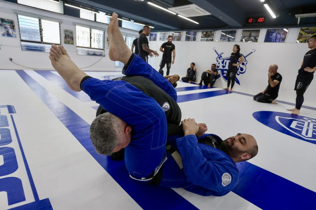 Nosherwan Khanzada (in blue), co-founder of Espada Studio, and student Anthony Hollis (in black) demonstrate an arm bar at the Brazilian jiu-jitsu gym in Sheung Wan, Hong Kong. Photo: Jonathan Wong