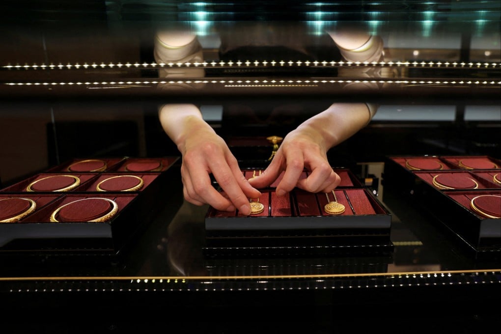 A staff member arranges gold necklaces in a display case at a Laopu Gold jewellery store in Beijing. Photo: Reuters
