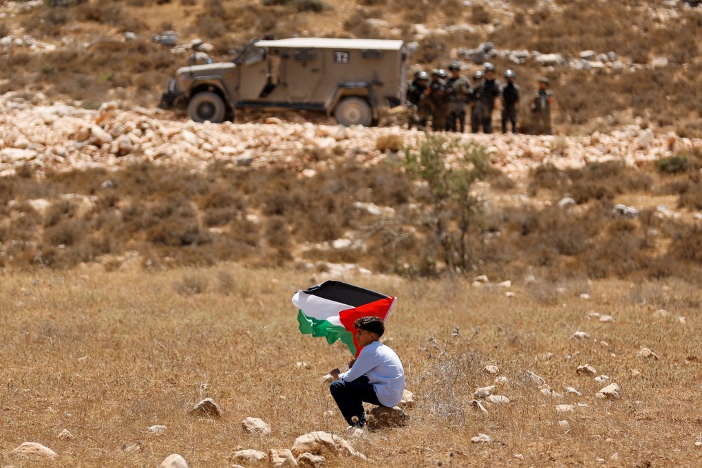 A boy holds a Palestinian flag during a demonstration against what Palestinians say is Israel’s confiscation of their land, as Israeli security forces stand guard, in the Israeli-occupied West Bank. Photo: Reuters