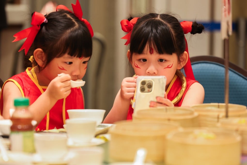 Children dressed up as Ne Zha are engrossed by a video on a smartphone as they have dim sum in a restaurant in Tsuen Wan on July 22. Photo: Nora Tam