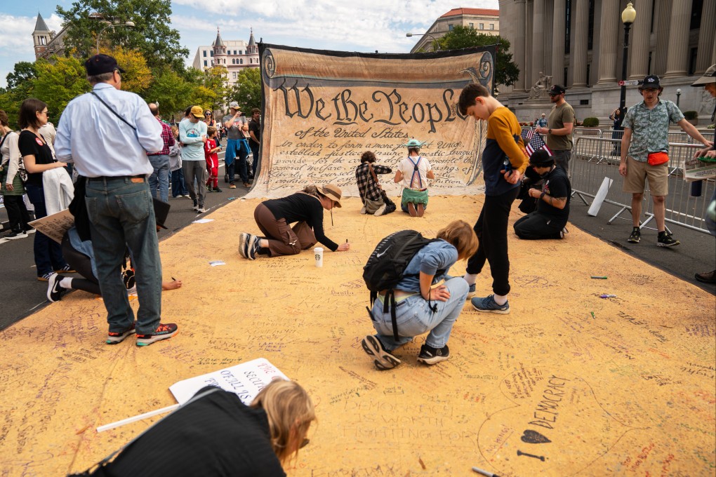 People sign a banner representing the US Constitution during a “No Kings” protest on October 18 in Washington. Photo: AP