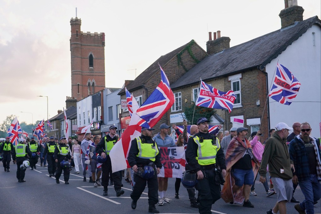 Police officers escort protesters near the Bell Hotel in Epping, London, on August 31, after a temporary injunction that would have blocked asylum seekers from being housed at the hotel was overturned, including Hadush Gerberslasie Kebatu. Photo: AP