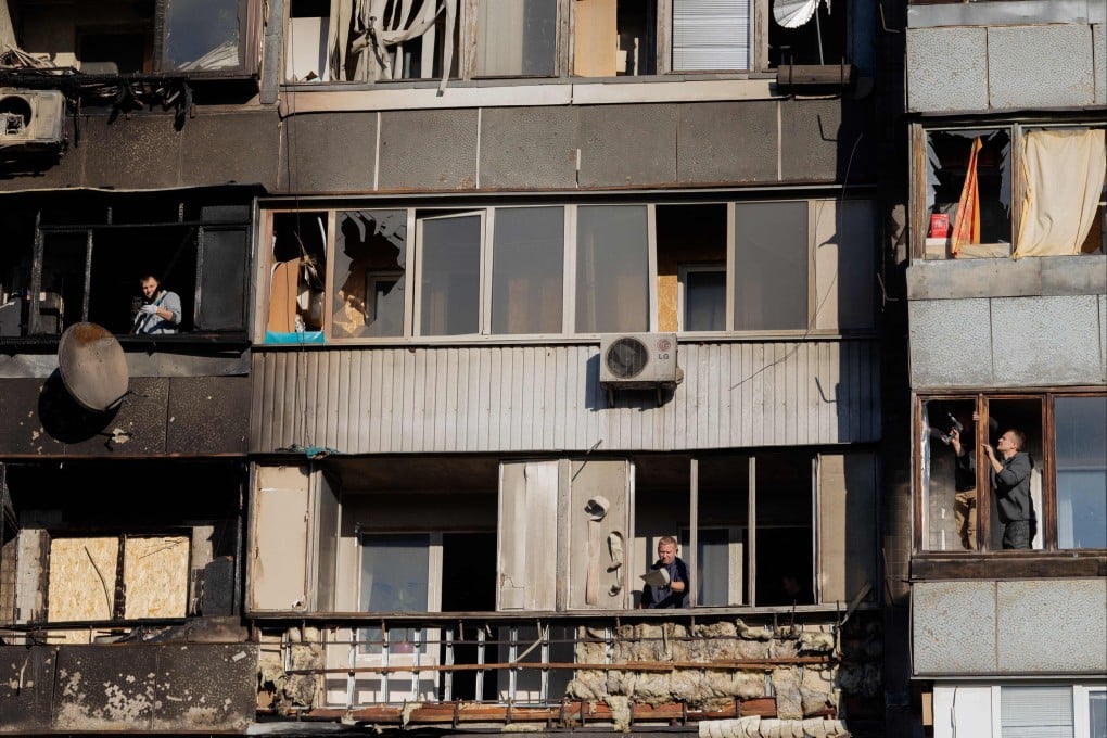 Local residents clean up glass from their broken windows following a drone attack in Kyiv. Photo: AFP