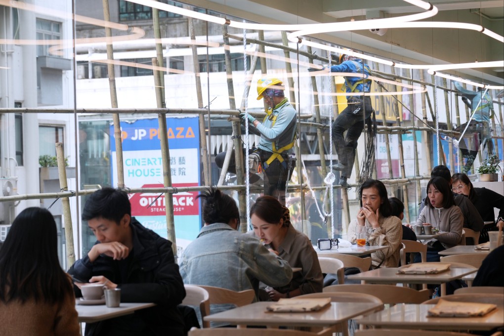 Workers fix scaffolding adjacent to a building in Causeway Bay as people eat at a restaurant, on April 1. Photo: Sam Tsang