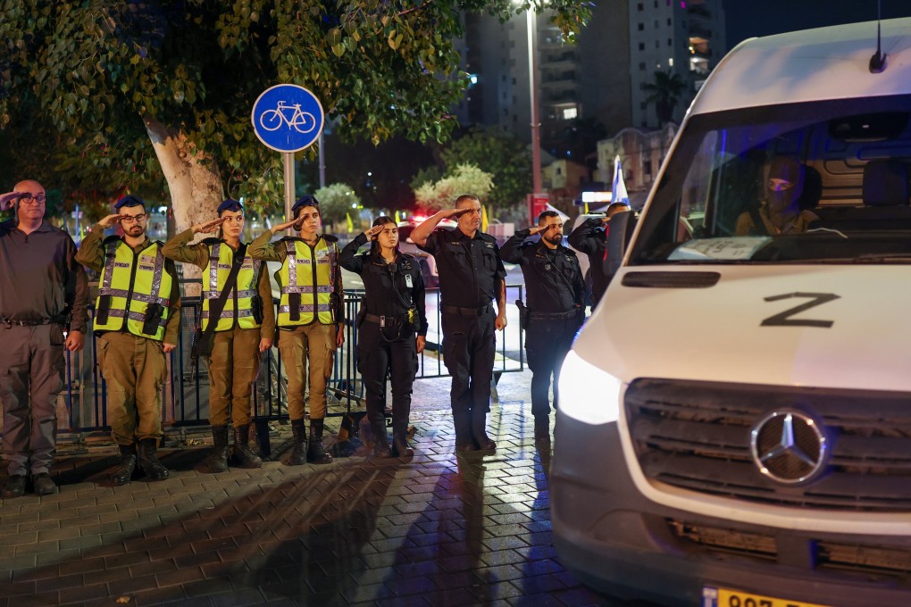 Israeli soldiers and police salute as a convoy carrying the body of a hostage arrives in Tel Aviv on Tuesday. Photo: EPA