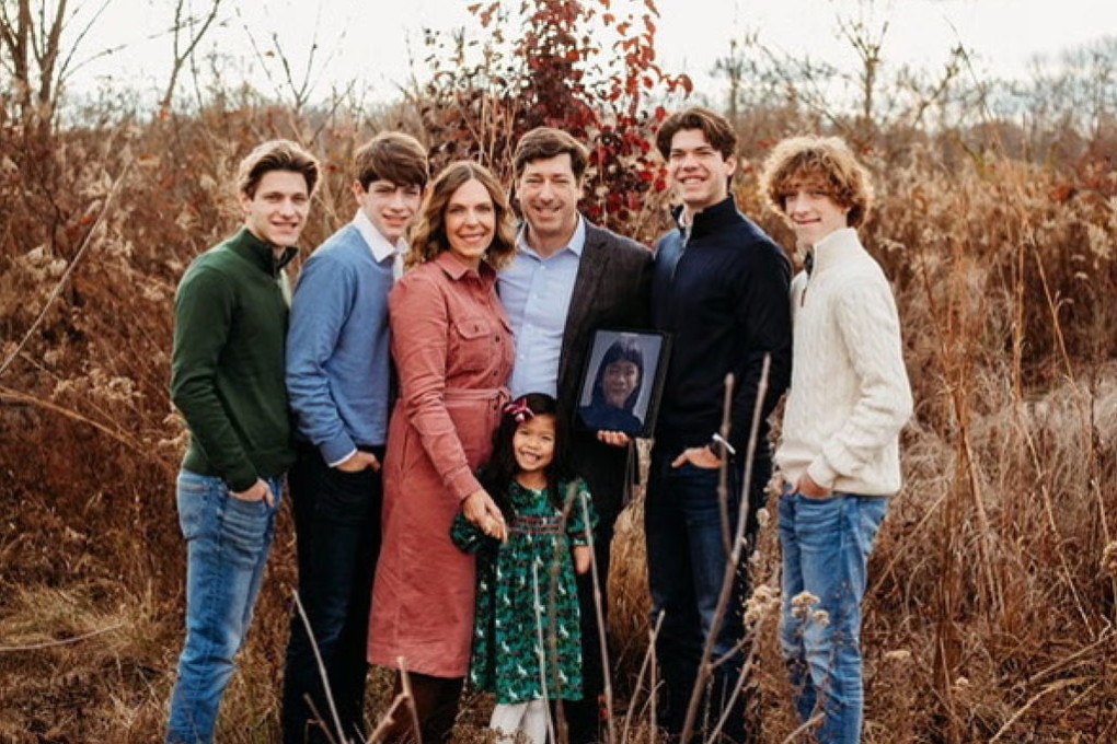 Aimee and Stephen Welch hold a photo of the girl they hope to adopt and name Penelope. They are pictured with their family, including their daughter, Grace, who was adopted from China in 2017. Photo: Welch family
