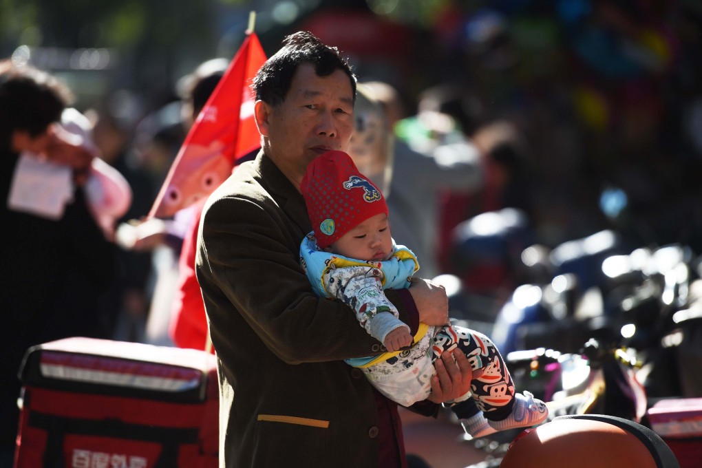 A man holds a baby on a path outside a children’s hospital in Beijing on October 30, 2015. Photo: AFP