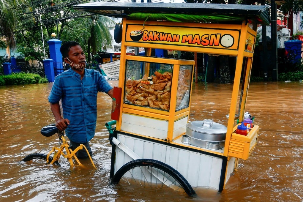 A street vendor pushes his cart through floodwaters following heavy rains in Jakarta. Photo: Reuters