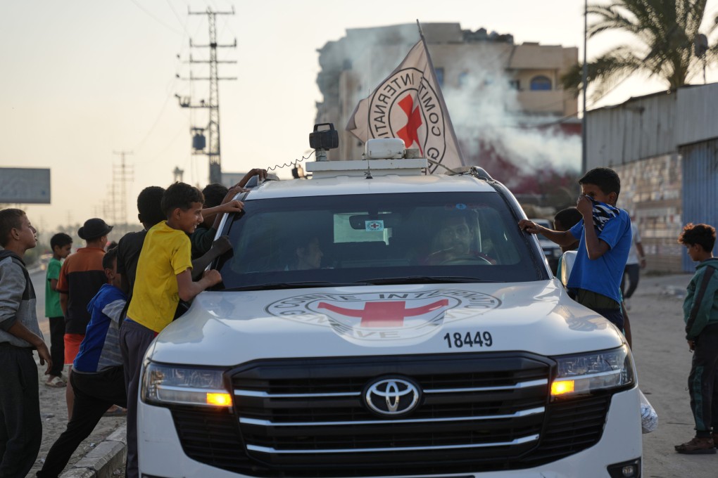 Palestinian kids look into a Red Cross vehicles carrying the bodies of deceased hostages handed over by Hamas on Thursday. Photo: AP