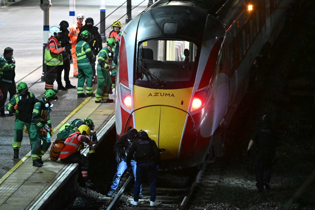 Police officers and members of the emergency services search the track beneath a train at Huntingdon Station on Saturday. Photo: AFP