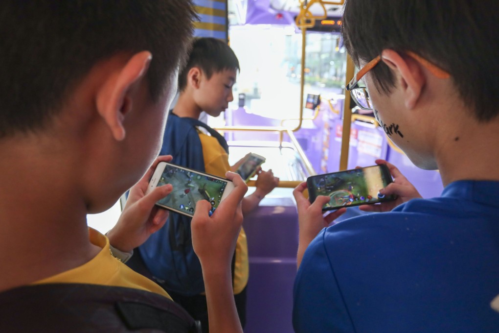Boys play games on their smartphones on a bus in Hong Kong. Photo: Jonathan Wong