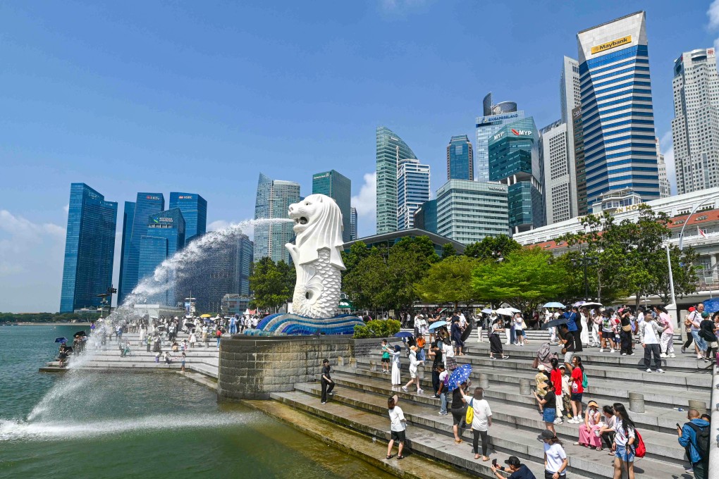 People take pictures next to the Merlion statue at the Marina Bay waterfront in Singapore. The city state has passed a law punishing scammers with six to 24 strokes of the cane. Photo: AFP