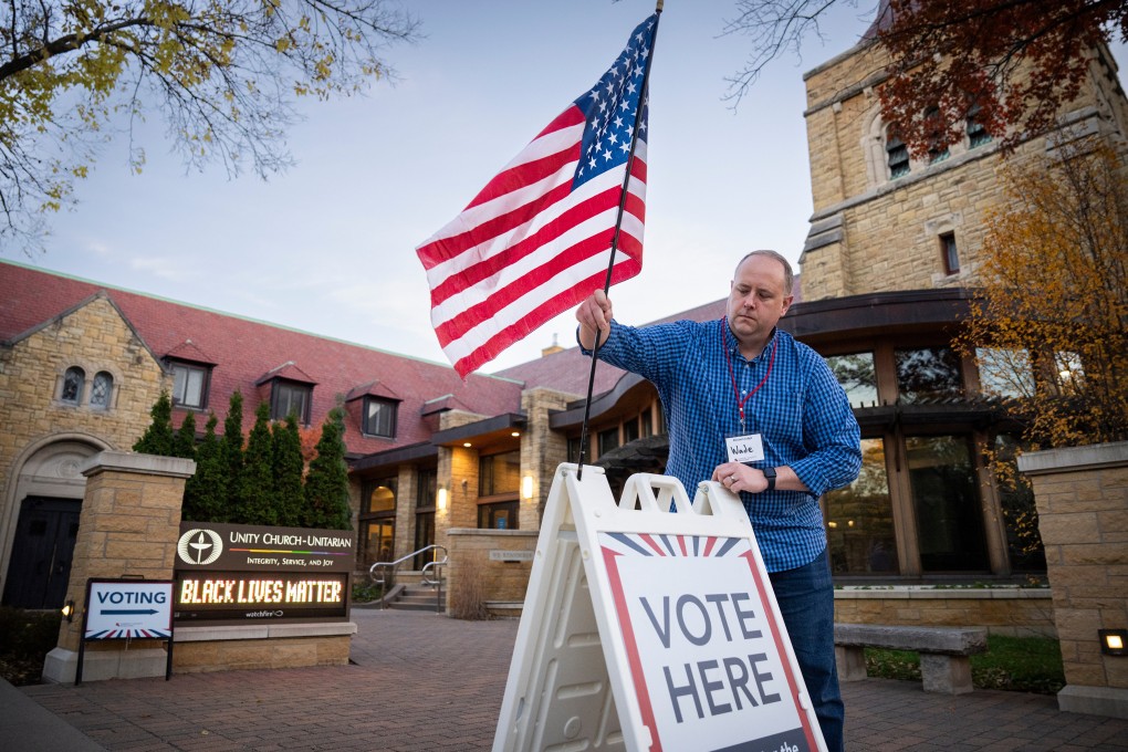 Wade Gustafson, a volunteer election judge, puts up an American flag and voting signs in St Paul, Minnesota, on Tuesday. Photo: Star Tribune via AP