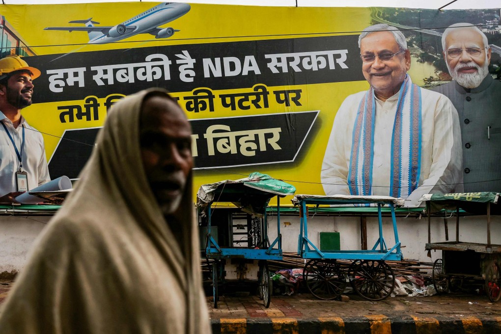 A man walks past a banner showing Indian Prime Minister Narendra Modi (right) and Bihar Chief Minister Nitish Kumar (second right) in Patna on Saturday ahead of the state assembly elections. Photo: AFP