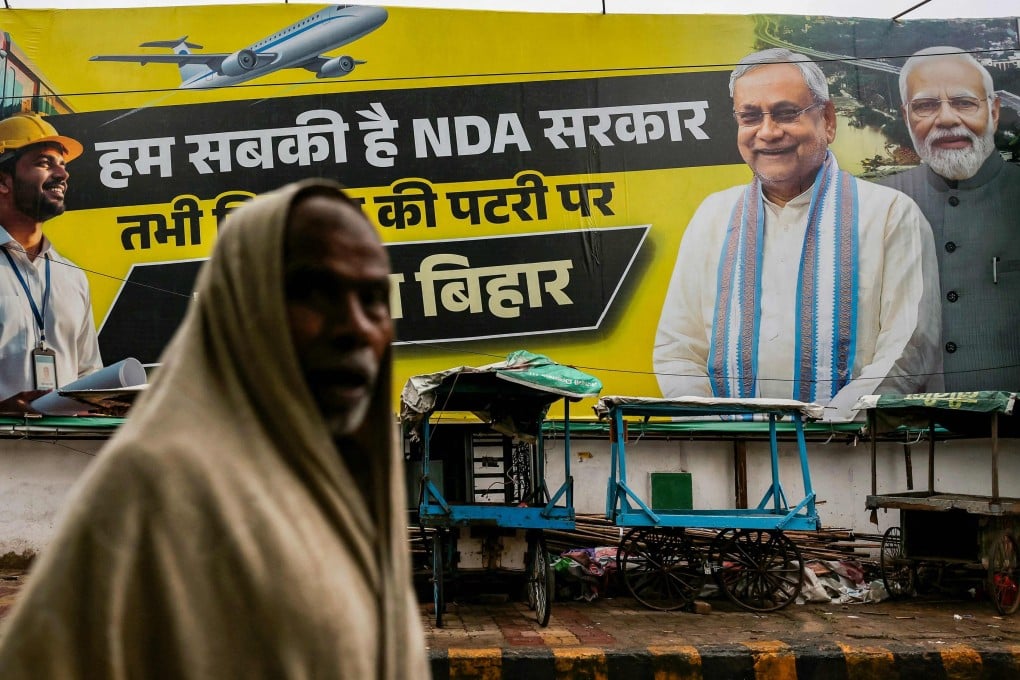 A man walks past a banner showing Indian Prime Minister Narendra Modi (right) and Bihar Chief Minister Nitish Kumar (second right) in Patna on Saturday ahead of the state assembly elections. Photo: AFP