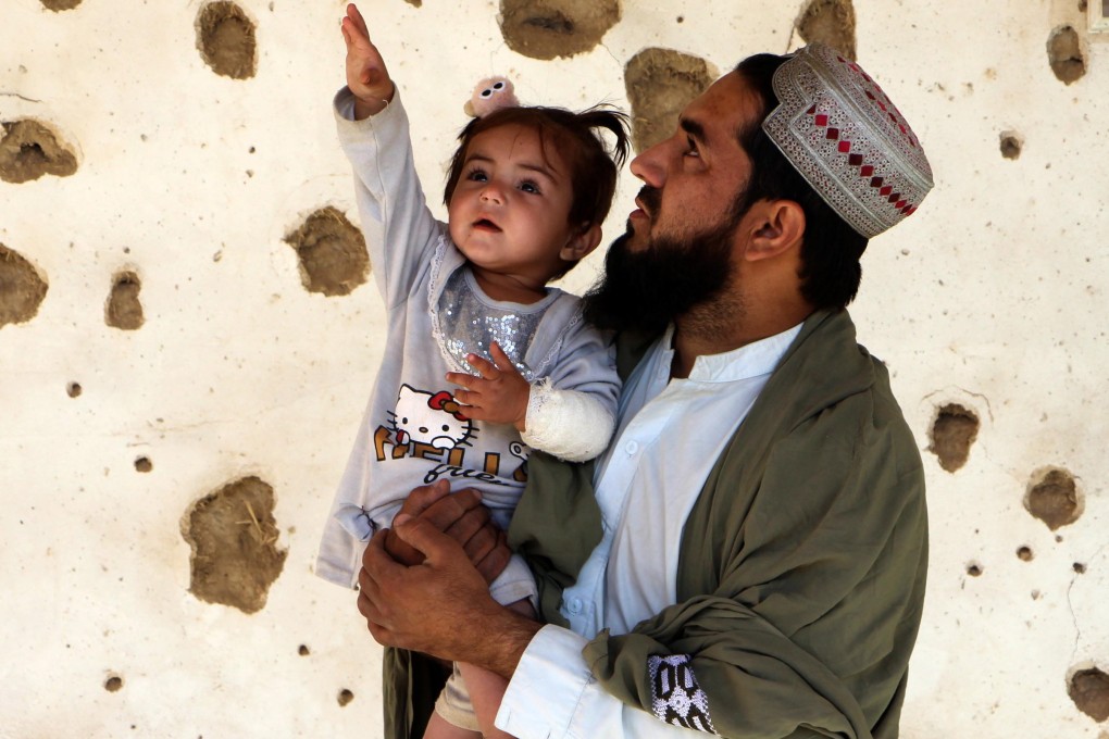 A man and child stand by a house allegedly damaged by cross-border fire from Pakistan in Spin Boldak, Afghanistan, on Friday. Photo: EPA