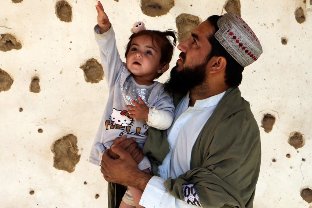 A man and child stand by a house allegedly damaged by cross-border fire from Pakistan in Spin Boldak, Afghanistan, on Friday. Photo: EPA
