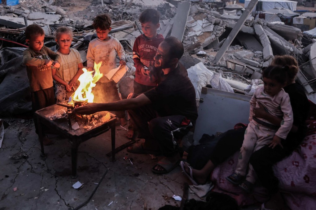 A Palestinian family sits around a fire amid the rubble of destroyed buildings in Jabalia, in the northern Gaza Strip, on Friday. Photo: AFP