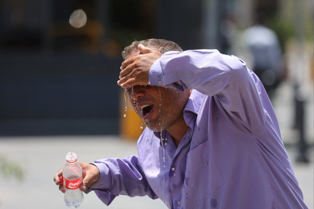 An Iranian taxi driver splashes water on himself to cool down during intense heat in Tehran. File photo: Reuters
