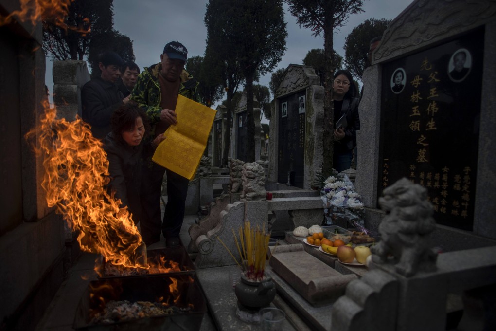 Ghost money and incense sticks are burnt in front of a gravestone during the Ching Ming Festival at a cemetery in Shanghai in 2017. Photo: AFP