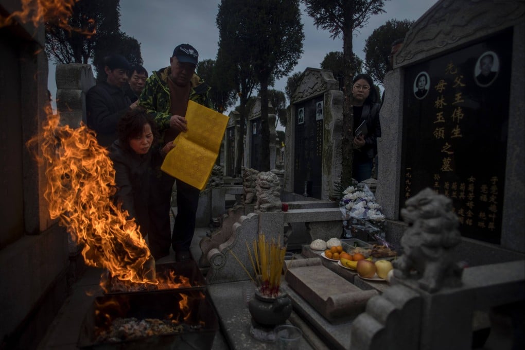 Ghost money and incense sticks are burnt in front of a gravestone during the Ching Ming Festival at a cemetery in Shanghai in 2017. Photo: AFP
