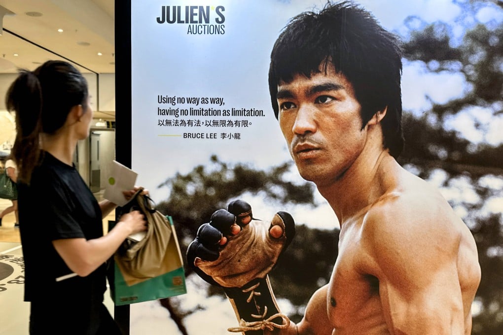 A woman looks at a Bruce Lee poster in Hong Kong in 2024. Half a century after his death, Lee is still an icon from Asia to the United States. Jeff Chang considers why in his biography of the kung fu movie star. Photo: Zuma Press/TNS