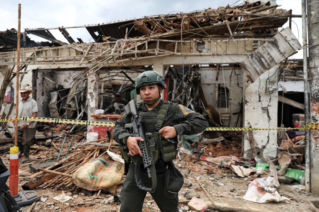 A police officer stands in front of a building damaged in an attack blamed by the military on Farc dissidents in Mondomo, Colombia, on Saturday. Photo: AP