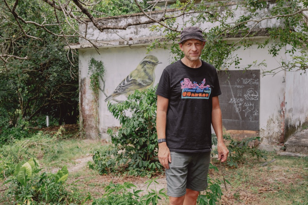 Dominic Johnson-Hill in front of a mural featuring a yellow-browed warbler in Mui Wo, Lantau Island. Photo: Jocelyn Tam