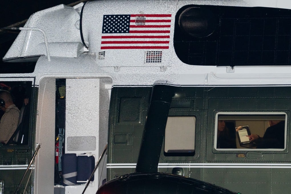 US President Donald Trump reads text from a laptop aboard Marine One on Sunday. Photo: AP