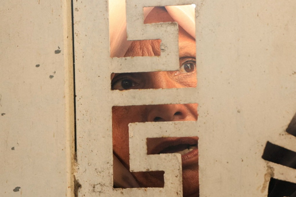 A woman looks through a gate as Palestinians wait to buy bread from a distribution point in Khan Younis in the southern Gaza Strip on November 17. Photo: Reuters