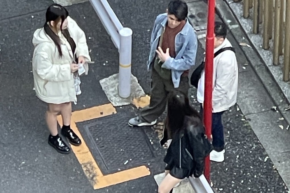 Men approach young women standing on a street corner in Tokyo, Japan. Photo: Eric Fior