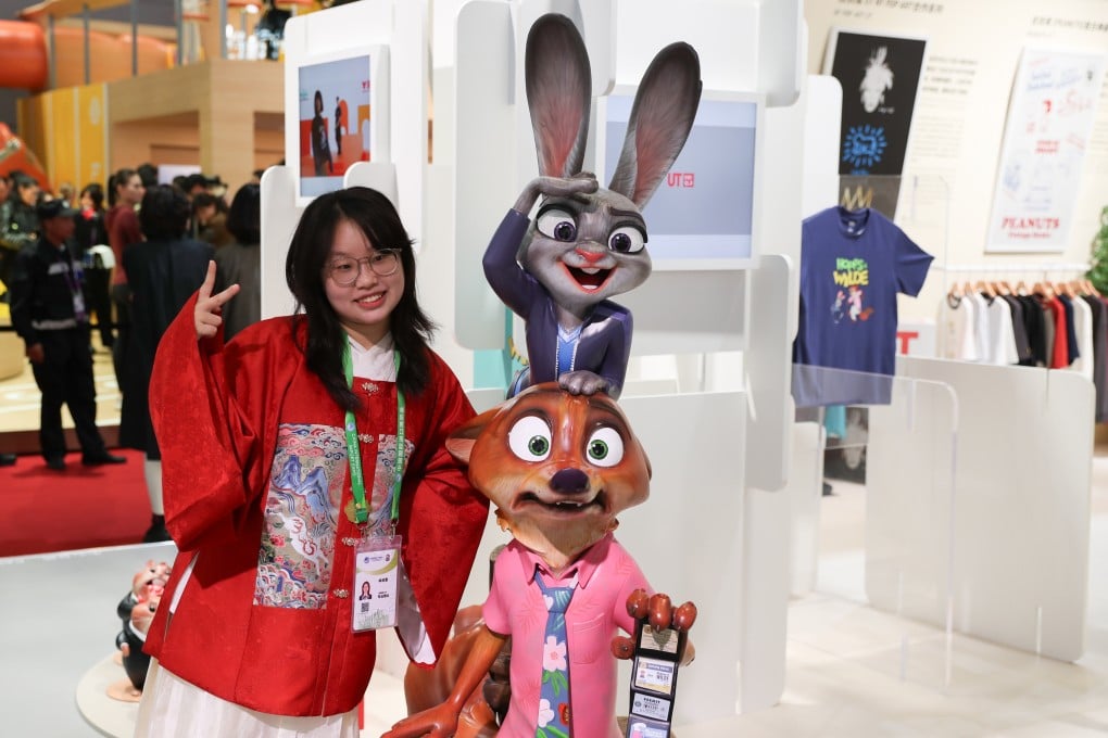 A young woman poses for a photo next to a booth showcasing Zootopia-branded merchandise sold by the retail chain Uniqlo at an exhibition in Shanghai. Photo: Xinhua