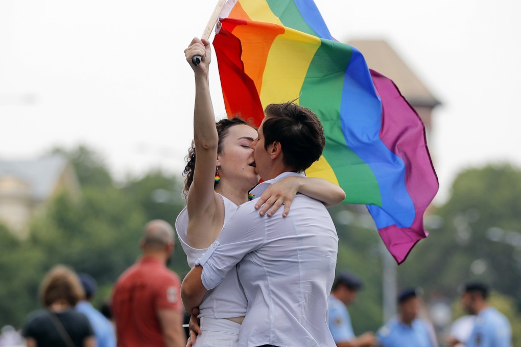 Two girls kiss holding a rainbow flag during the gay pride parade in Bucharest, Romania in 2018. Photo: AP