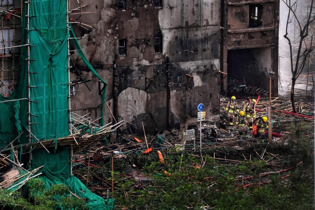 Firefighters emerge from a building in Wang Fuk Court. Questions have been raised about the green netting used on the bamboo scaffolding Photo: Elson Li