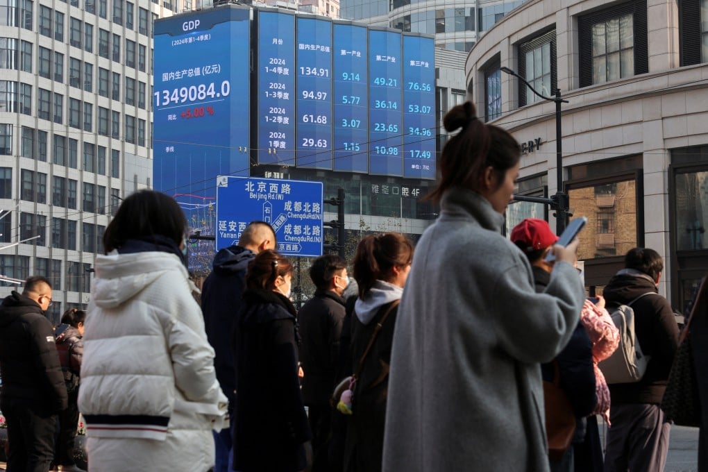 Pedestrians wait for a street signal on a sidewalk as an electronic billboard shows China’s 2024 gross domestic product growth in Shanghai, taken on January 21 this year. Photo: Reuters