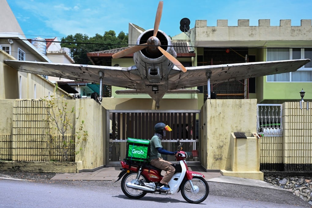 A delivery rider for Grab passes in front of a house in Kuala Lumpur, Malaysia. Photo: AFP