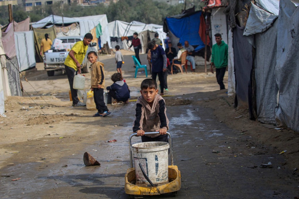 A boy pushes a bucket for water at a camp for displaced Palestinians in Gaza on Saturday. The level of violence in the enclave has reduced since a ceasefire began last month, but Israel has continued its strikes. Photo: AFP