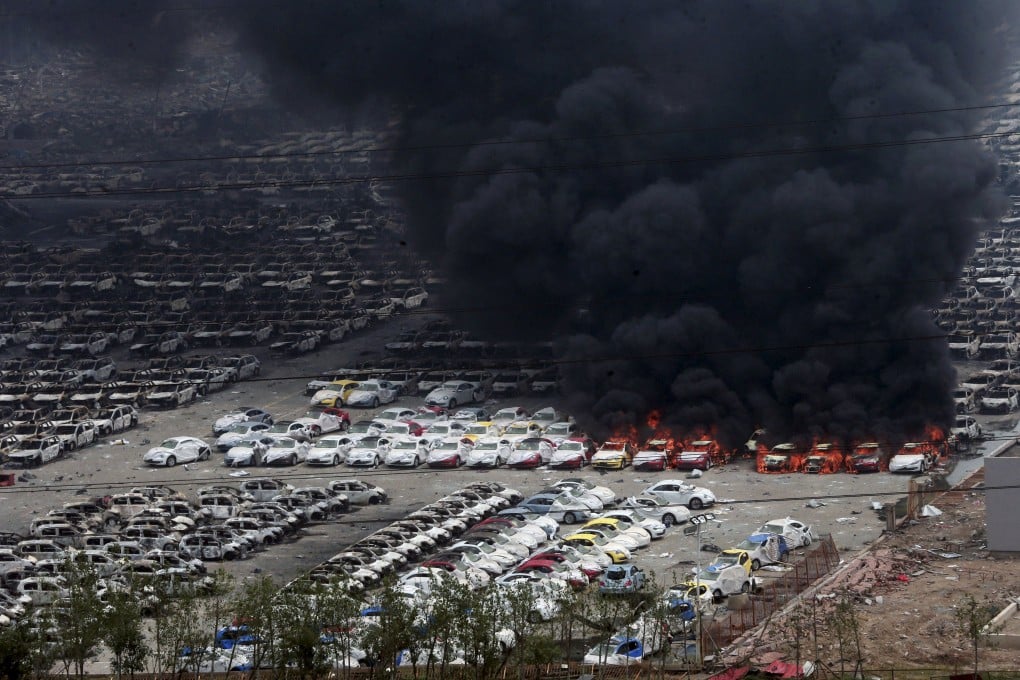 Smoke rises as damaged vehicles are seen burning near the site of explosions in  Binhai New District of Tianjin,  northern China, in August 2015. Photo: Reuters