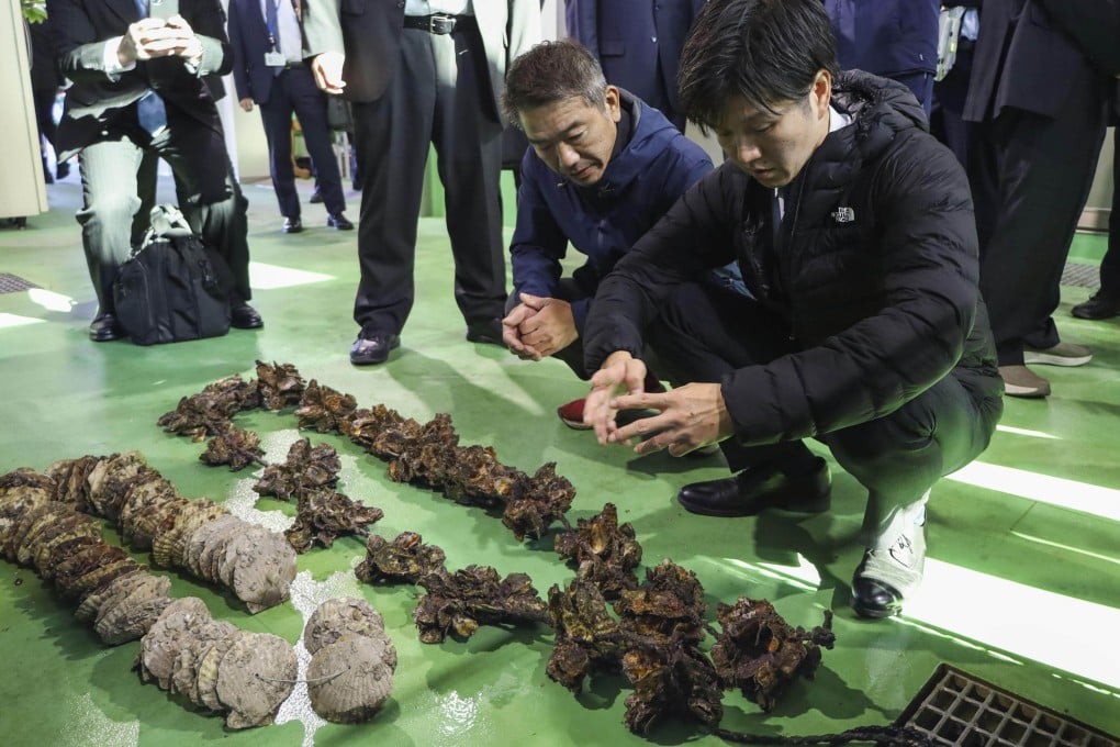 Japanese Agriculture, Forestry and Fisheries Minister Norikazu Suzuki (right) is briefed by an oyster farmer in Hiroshima Prefecture, last month following reports of mass die-offs of the shellfish. Photo: Kyodo